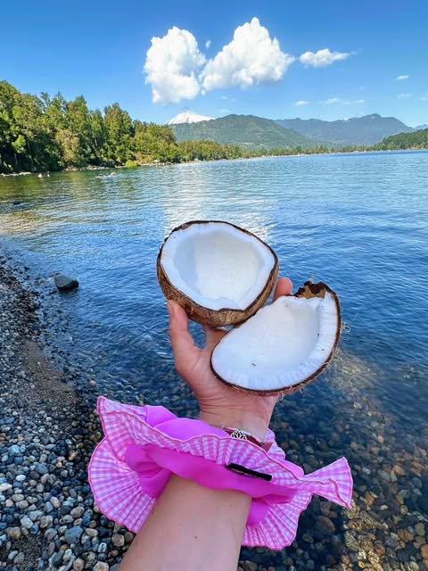 Coco abierto en la orilla del lago con coleta rosada