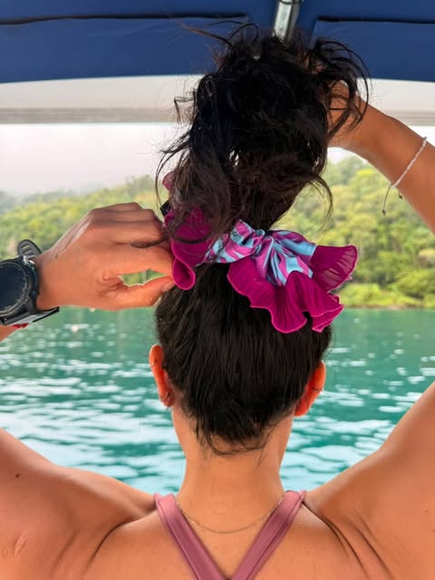 Moño alto con coleta plisada fucsia en un bote en el lago